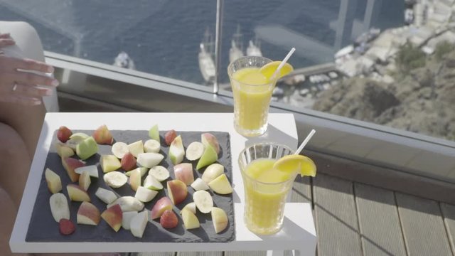 slow motion video closeup taking fresh orange juice from little table with fruits at poolside on volcanic island
