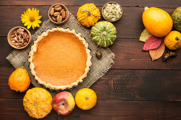 pumpkin homemade pie at wooden background arranged with food ingredients top view