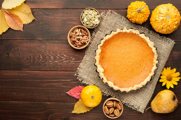 pumpkin homemade pie at wooden background arranged with food ingredients top view