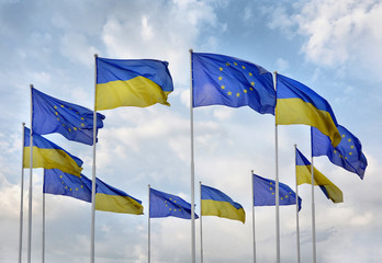 Flags of Ukraine and European Union (EU) against the blue sky.