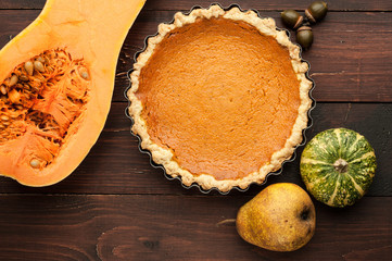 Obraz na płótnie Canvas pumpkin homemade pie at wooden background arranged with food ingredients top view