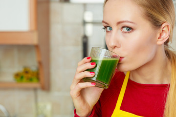 Woman in kitchen holding vegetable smoothie juice