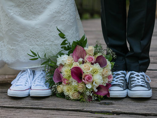 Brautpaar mit lustigen Hochzeitsschuhen und wunderschönem Brautstrauss