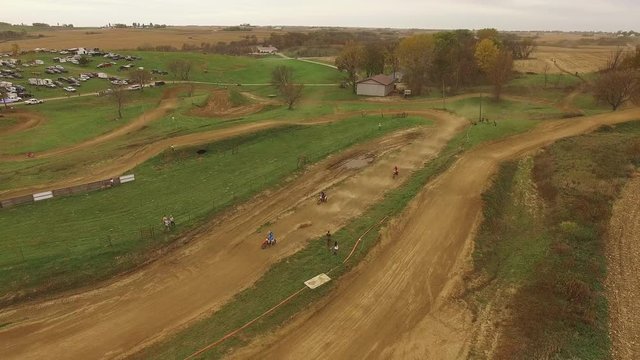 People race dirt bikes on dirt raceway, aerial
