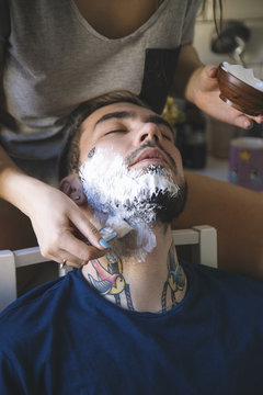 Woman smearing shaving foam on man's beard