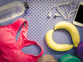 colorful from pink sportswear and refresh energy by banana and relax by listen music with smart phone and earphones with soft focus yoga mat background