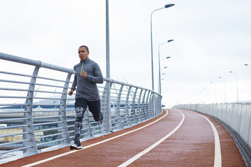 Healthy active lifestyle concept. Attractive young African male jogger exercising at stadium alone...