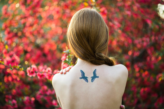 Woman With Bird Tattoo in a Spring Garden