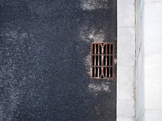 Asphalt city road, top view. Stone fence, drainage grate for rainwater