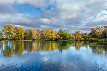 The lake, reflecting the cloudy sky and autumnal foliage trees