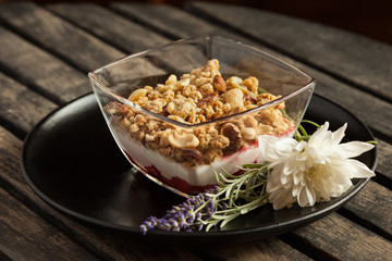 Granola dessert with vanilla and strawberry cream on wooden table - Close up