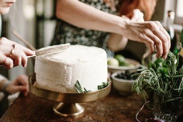Females decorate homemade cake with white icing and rosemary