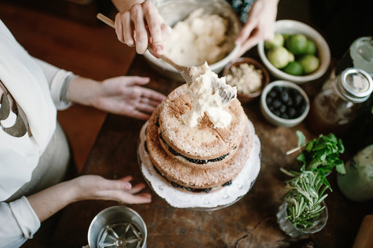 Two tierd naked layer cake is decorated by two females