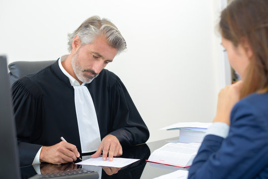 lawyer signing a document in an office with female client