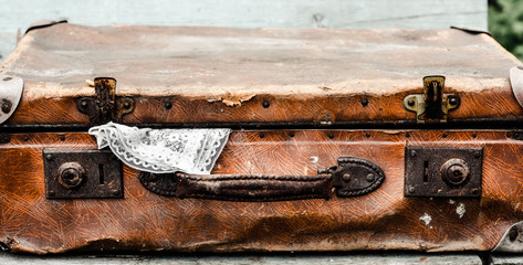 On the bench is a suitcase. Out of a suitcase sticking out a piece of handkerchief.
