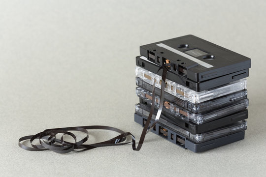 Stack of audio cassette tape with loose tape spilling from top cassette.
