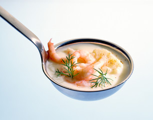 Cauliflower soup with shrimps in a ladle