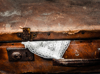 On the bench is a suitcase. Out of a suitcase sticking out a piece of handkerchief.
