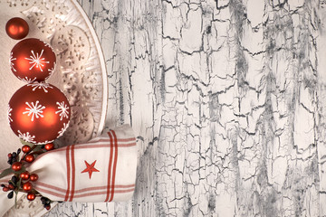 Decorative plate with red Christmas baubles on rustic background