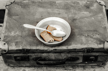 Vintage suitcase is lying on the bench. The suitcase is metal plate with a spoon. In the bowl of bread.
