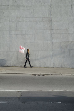 Young woman holding colorful pink balloons