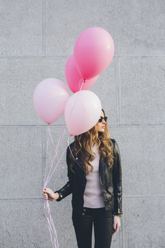 Young woman holding colorful pink balloons