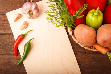Fresh vegetables, pepper, carrots, potatoes, cabbage and garlic in a basket on a wooden background. Background. Autumn, harvest. Thanksgiving Day. Space for text.