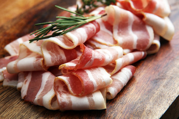 Raw sliced bacon with thyme leaves ready for cooking.