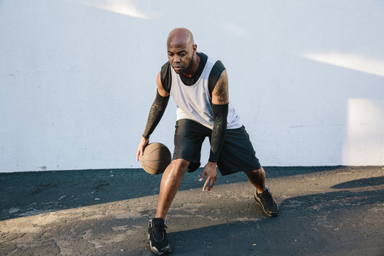 Man dribbling basketball on asphalt 