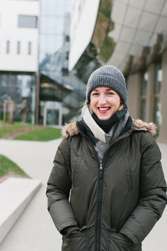 Smiling woman in winter coat near building