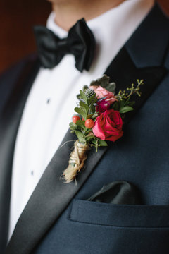 Mid section of a groom wearing tuxedo with boutonniere