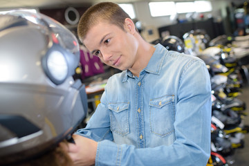 young man choosing motorbike helmet