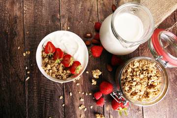 Healthy breakfast concept with oat flakes and fresh berries on rustic background. Food made of granola and musli. Healthy muesli with strawberries, nuts and milk.