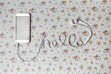 Hello written with a cellphone cable on a floral pattern background