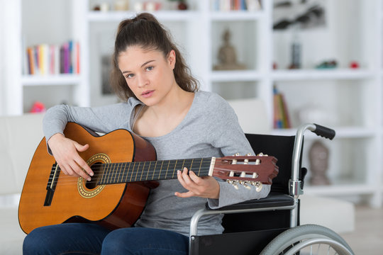 young female musican on wheelchair playing classical guitar