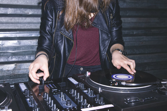 Young female DJ playing music at DJ desk
