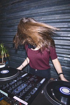 Young female DJ having fun at DJ board