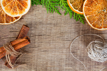 On a woody background, spices are laid out: lemon, cinnamon and greens cypress branches