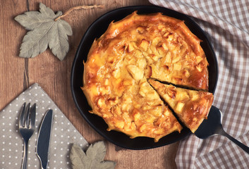 Homemade round apple pie with a slice cut out on a black dish, top view