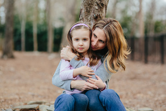 Beautiful mother holding her young daughter protectively