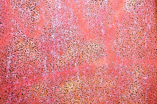 Close up view of a colorful red corroded wall with little holes