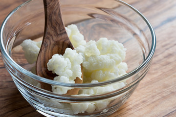 Kefir grains in a glass bowl with a wooden spoon