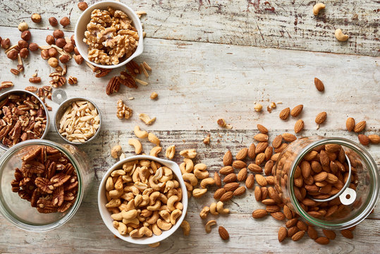 Different nuts in jars on wooden table