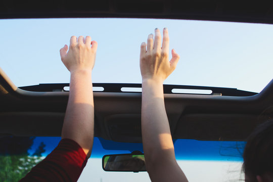 hands reaching out of sunroof on warm day