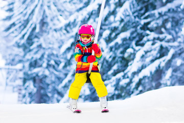 Fototapeta na wymiar Child on ski lift in snow sport school in winter mountains