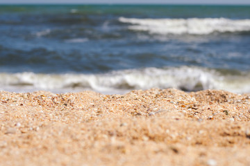 Close-up of yellow sand on the beach and sea waves in the background