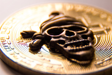 Macro shooting of the symbol of the pirate skull against the background of the gold coin of the crypto currency.