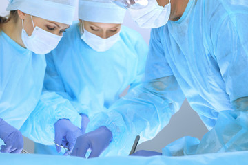 Medical team performing operation. Three of surgeons at work are busy of patient. Medicine,...