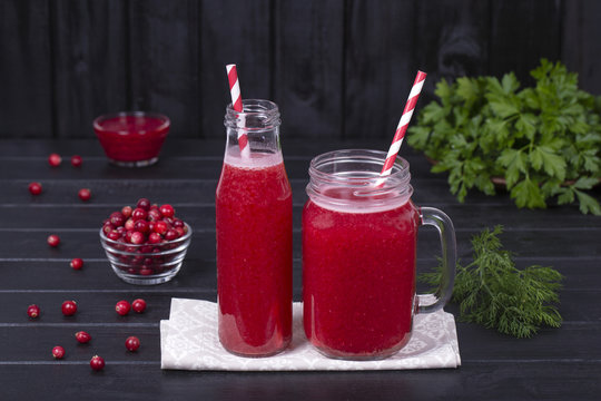 Cranberry juice and raw cranberry on black wooden background, close up