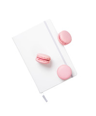 Three pink macaroon cookies and white notepad book isolated
